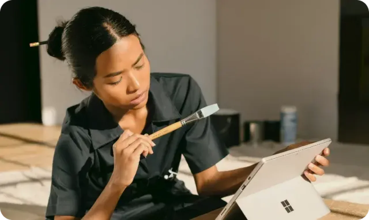 A Woman Sitting On A Box Holding A Paintbrush
